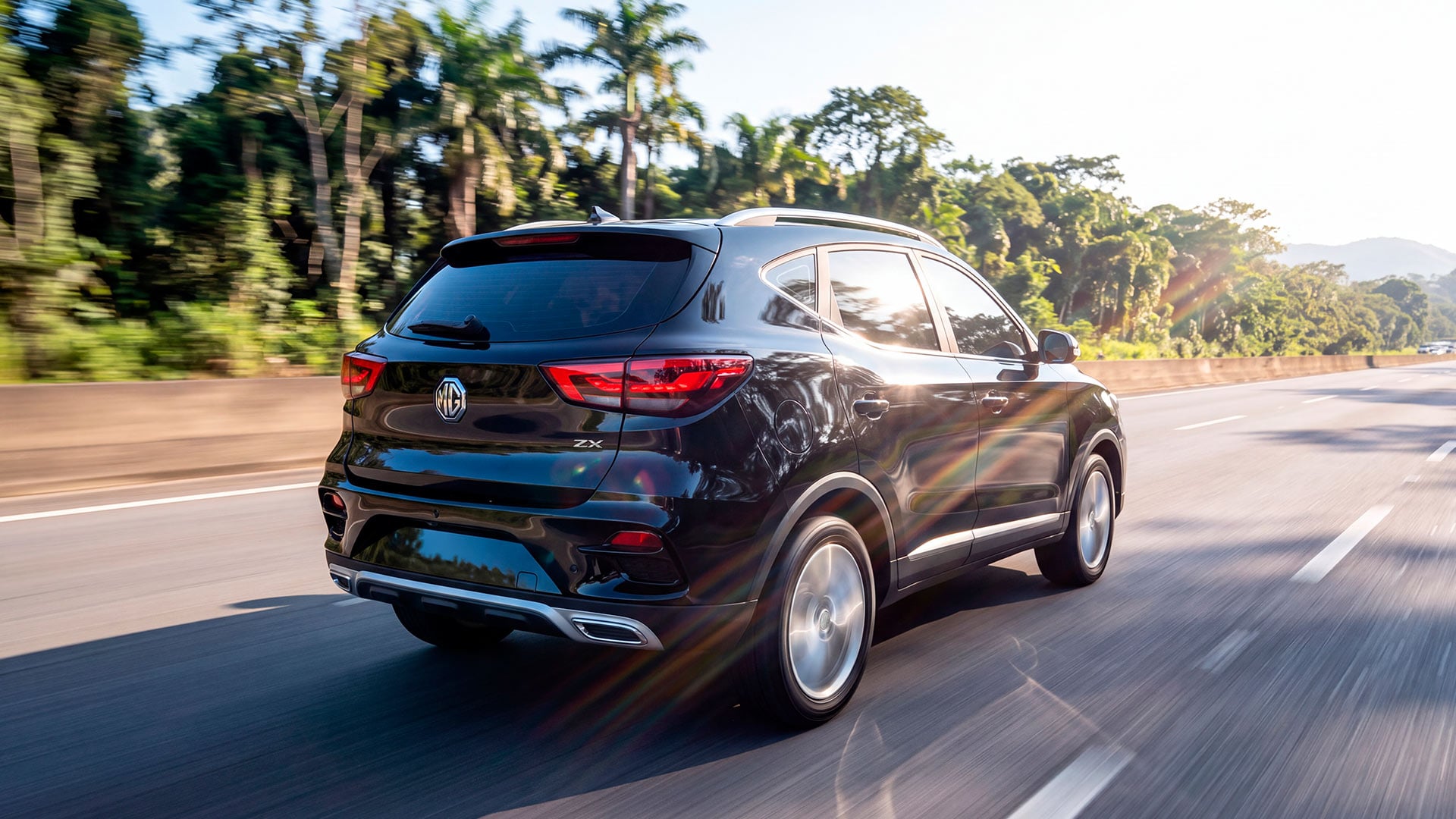SUV MG ZX negro en movimiento por una autopista, vista trasera lateral con luces LED